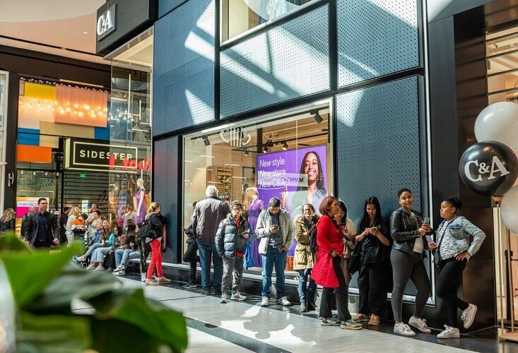 Interessierte Kund:innen warten vor dem Store, um an der Eröffnung teilzunehmen.