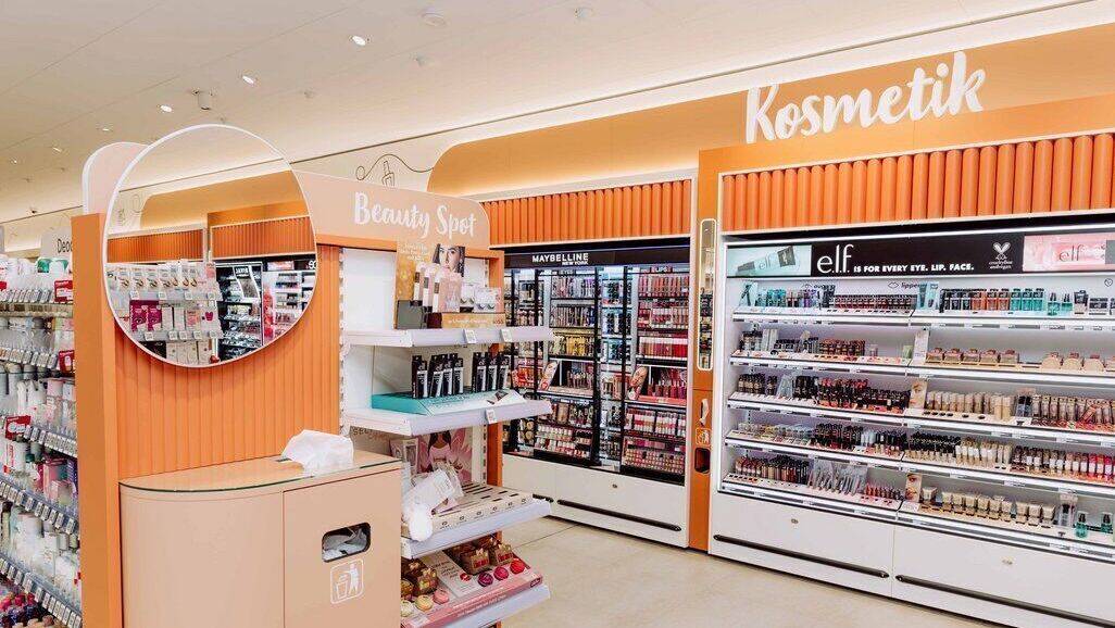 Der Kosmetikbereich ist in warmem Orange gehalten. Ein Schminktisch lädt zum Ausprobieren ein.