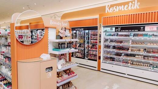 Der Kosmetikbereich ist in warmem Orange gehalten. Ein Schminktisch lädt zum Ausprobieren ein.