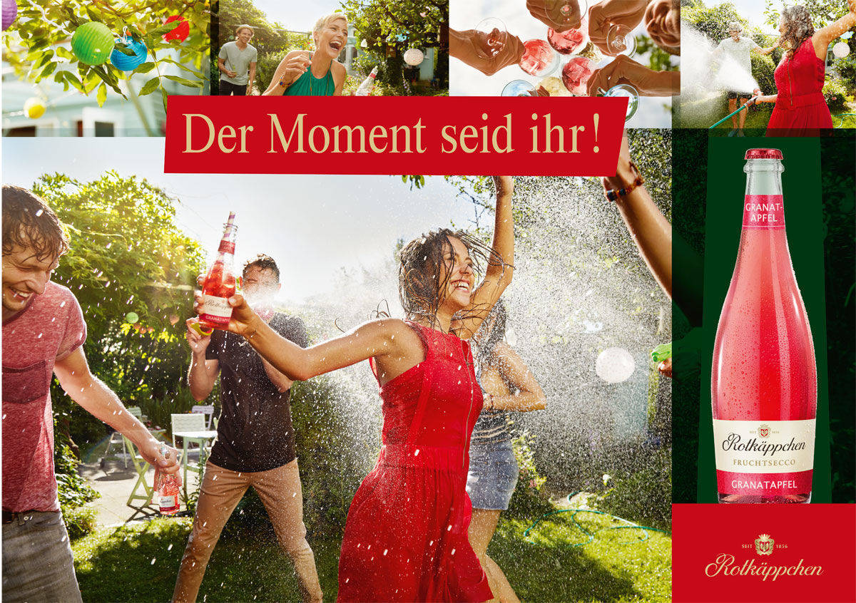 Die Frau im roten Kleid feiert im Sommer 2018 mit Fruchtsecco. 